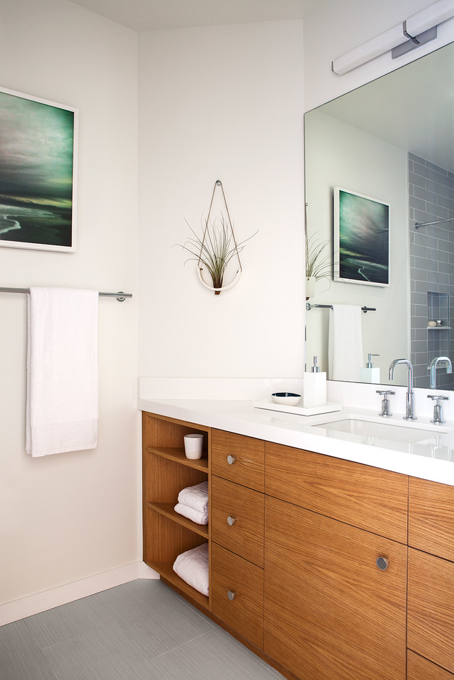 Small contemporary bathroom in San Francisco with a submerged sink, flat-panel cabinets, medium wood cabinets, engineered stone worktops, an alcove bath, a shower/bath combination, a two-piece toilet, grey tiles, ceramic tiles, white walls and ceramic flooring.