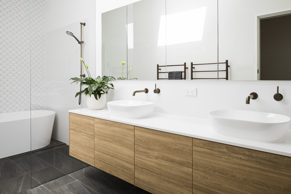 Large contemporary bathroom in Other with flat-panel cabinets, medium wood cabinets, a freestanding bath, white tiles, white walls, a vessel sink, grey floors, an open shower, white worktops and a built in vanity unit.