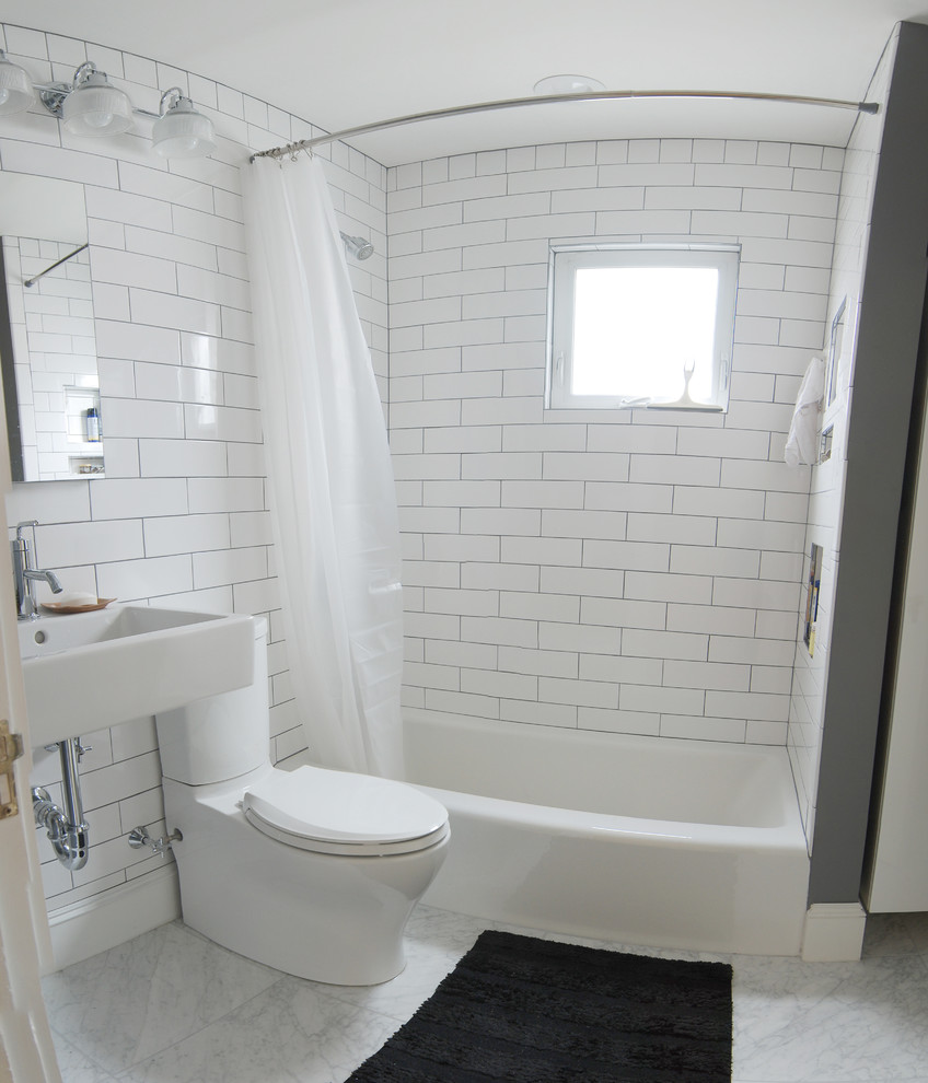 Small modern bathroom in Boston with a wall-mounted sink, an alcove bath, a shower/bath combination, a two-piece toilet, white tiles, metro tiles, grey walls and marble flooring.