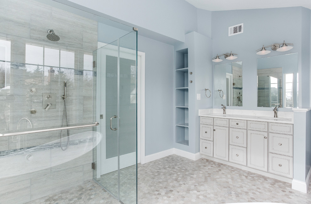 Photo of a medium sized classic ensuite bathroom in DC Metro with raised-panel cabinets, grey cabinets, a freestanding bath, a built-in shower, a two-piece toilet, beige tiles, porcelain tiles, blue walls, mosaic tile flooring, a submerged sink, engineered stone worktops, beige floors, a hinged door and white worktops.