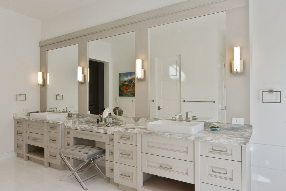 Стильный дизайн: огромная главная ванная комната в стиле неоклассика (современная классика) с фасадами с утопленной филенкой, бежевыми фасадами, отдельно стоящей ванной, душем в нише, унитазом-моноблоком, бежевой плиткой, керамогранитной плиткой, белыми стенами, мраморным полом, настольной раковиной, мраморной столешницей, белым полом и душем с распашными дверями - последний тренд