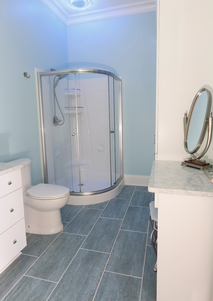 Design ideas for a medium sized coastal shower room bathroom in Wilmington with recessed-panel cabinets, white cabinets, a corner shower, a two-piece toilet, white tiles, glass tiles, blue walls, porcelain flooring, a vessel sink, solid surface worktops, blue floors, a sliding door and multi-coloured worktops.