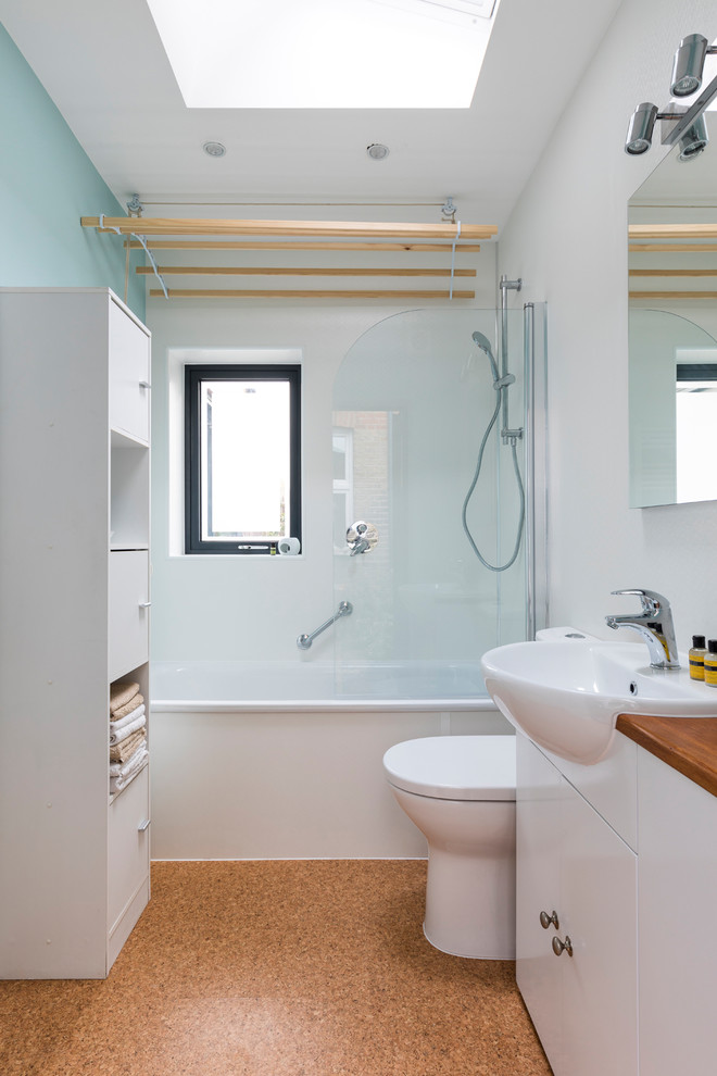 Пример оригинального дизайна: маленькая детская ванная комната в современном стиле с плоскими фасадами, белыми фасадами, ванной в нише, душем в нише, унитазом-моноблоком, плиткой из листового стекла, белыми стенами, пробковым полом, накладной раковиной, столешницей из дерева, коричневым полом, душем с распашными дверями и коричневой столешницей для на участке и в саду