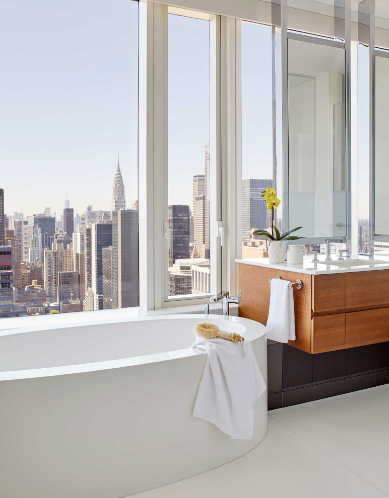 ニューヨークにあるコンテンポラリースタイルのおしゃれな浴室 (フラットパネル扉のキャビネット、中間色木目調キャビネット、置き型浴槽、アンダーカウンター洗面器、白い床、白い洗面カウンター、フローティング洗面台) の写真
