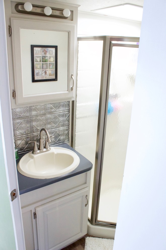 Пример оригинального дизайна: маленькая ванная комната в стиле рустика с белыми фасадами, угловым душем, унитазом-моноблоком, белыми стенами, полом из винила, душевой кабиной, накладной раковиной, столешницей из ламината, коричневым полом, душем с распашными дверями и серой столешницей для на участке и в саду