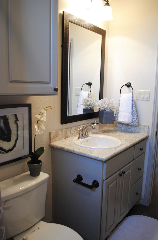 Medium sized eclectic family bathroom in Austin with recessed-panel cabinets, grey cabinets, a built-in bath, a shower/bath combination, a two-piece toilet, beige tiles, ceramic tiles, beige walls, vinyl flooring, a built-in sink and laminate worktops.