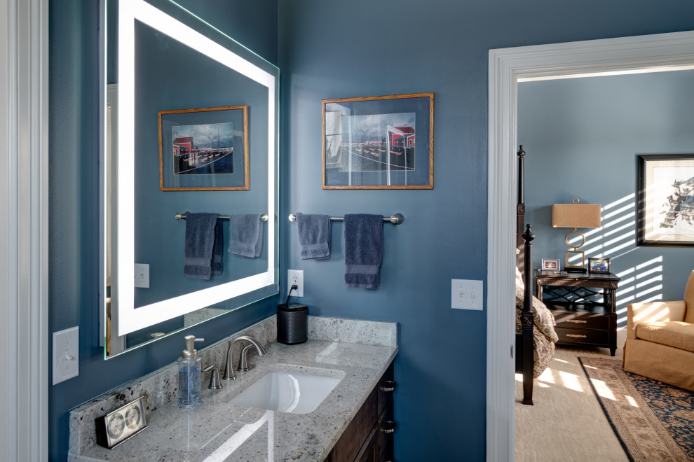 Cette image montre une salle de bain principale craftsman de taille moyenne avec un placard à porte shaker, des portes de placard marrons, un mur bleu, un lavabo encastré, un plan de toilette en granite et un plan de toilette gris.
