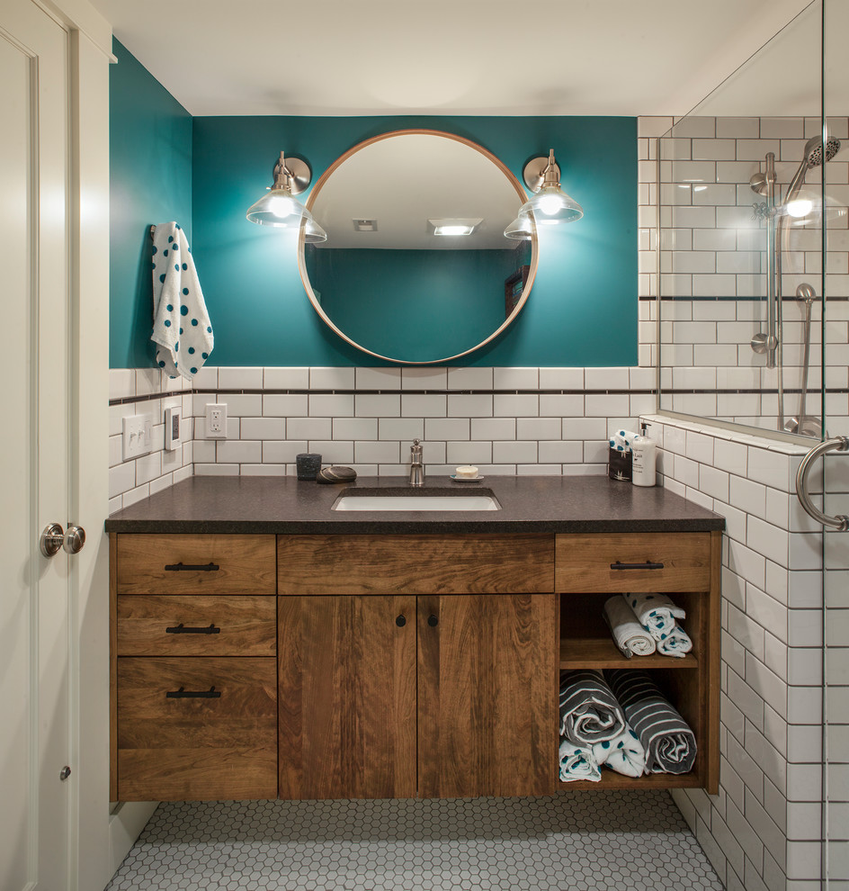 Bild på ett vintage brun brunt badrum, med släta luckor, skåp i mörkt trä, vit kakel, tunnelbanekakel, blå väggar, mosaikgolv, ett undermonterad handfat och vitt golv