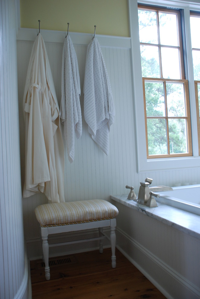 Ispirazione per una grande stanza da bagno padronale moderna con ante bianche, vasca freestanding, pareti gialle e pavimento in legno massello medio
