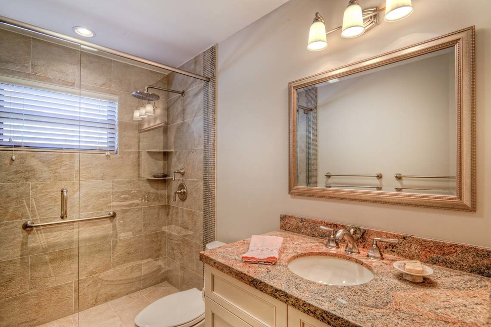 Idéer för ett mellanstort klassiskt badrum med dusch, med luckor med infälld panel, beige skåp, en dusch i en alkov, en toalettstol med separat cisternkåpa, brun kakel, stenkakel, grå väggar, ett undermonterad handfat och granitbänkskiva