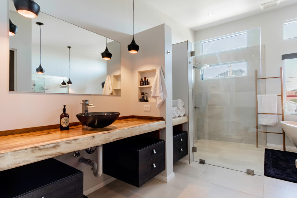 Idéer för ett mellanstort modernt en-suite badrum, med släta luckor, svarta skåp, en kantlös dusch, grå väggar, kalkstensgolv, ett fristående handfat, träbänkskiva och med dusch som är öppen