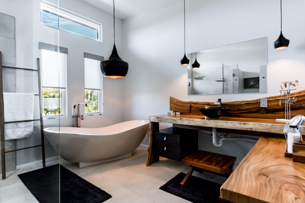 Medium sized modern ensuite bathroom in San Diego with flat-panel cabinets, a freestanding bath, a built-in shower, limestone tiles, grey walls, limestone flooring, a vessel sink, wooden worktops, an open shower, an enclosed toilet, a single sink, a floating vanity unit and a vaulted ceiling.