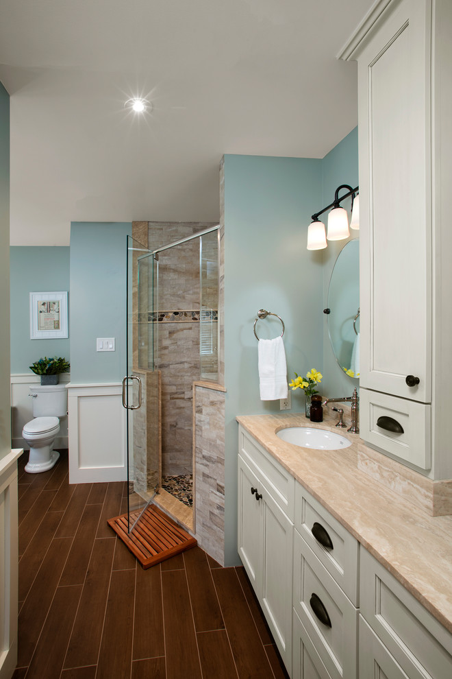 Стильный дизайн: большая главная ванная комната в стиле кантри с плоскими фасадами, бежевыми фасадами, ванной на ножках, угловым душем, раздельным унитазом, бежевой плиткой, керамогранитной плиткой, синими стенами, полом из керамогранита, врезной раковиной, столешницей из известняка, коричневым полом и душем с распашными дверями - последний тренд