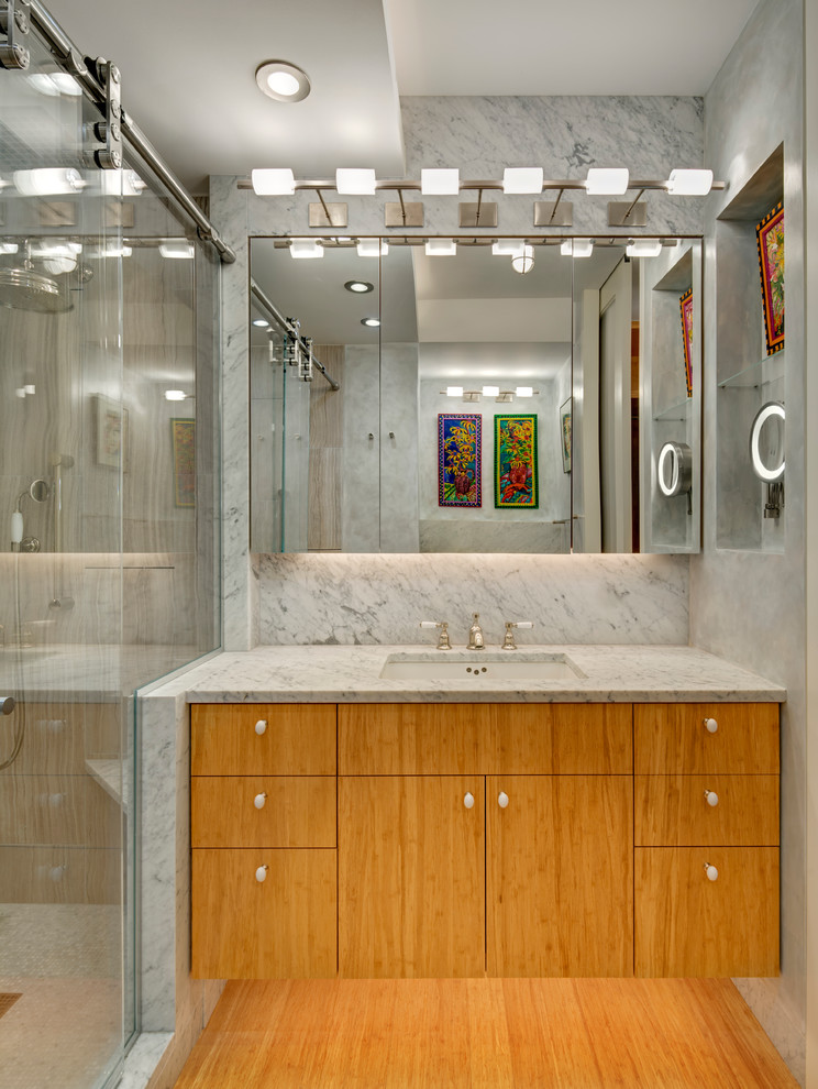 Modelo de cuarto de baño contemporáneo pequeño con armarios con paneles lisos, puertas de armario de madera clara, ducha empotrada, baldosas y/o azulejos grises, losas de piedra, paredes grises, suelo de bambú, lavabo bajoencimera y encimera de mármol