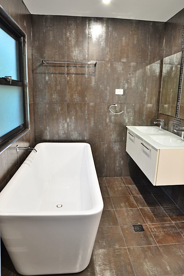 Cette photo montre une salle de bain principale bord de mer de taille moyenne avec un placard à porte plane, des portes de placard blanches, une baignoire indépendante et un lavabo posé.