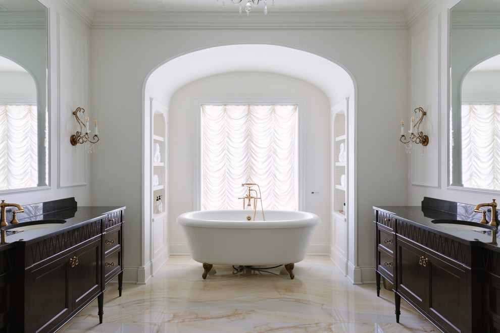 На фото: огромная главная ванная комната в классическом стиле с белыми стенами, врезной раковиной, разноцветным полом, черной столешницей, темными деревянными фасадами, ванной на ножках и фасадами с утопленной филенкой