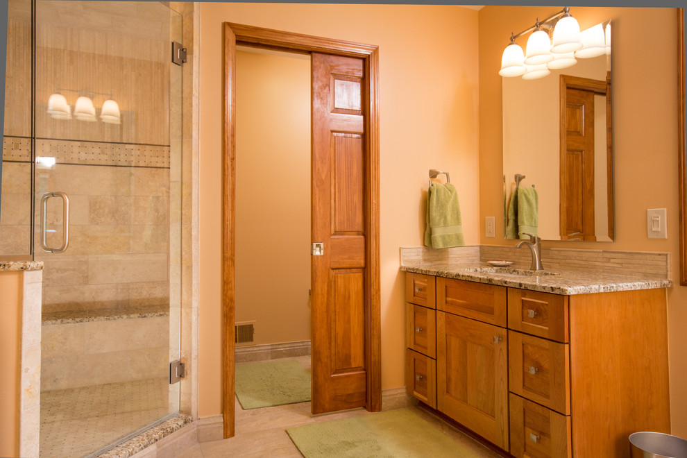 Стильный дизайн: ванная комната в стиле кантри с врезной раковиной, плоскими фасадами, столешницей из гранита, угловым душем, раздельным унитазом, бежевой плиткой, каменной плиткой и фасадами цвета дерева среднего тона - последний тренд