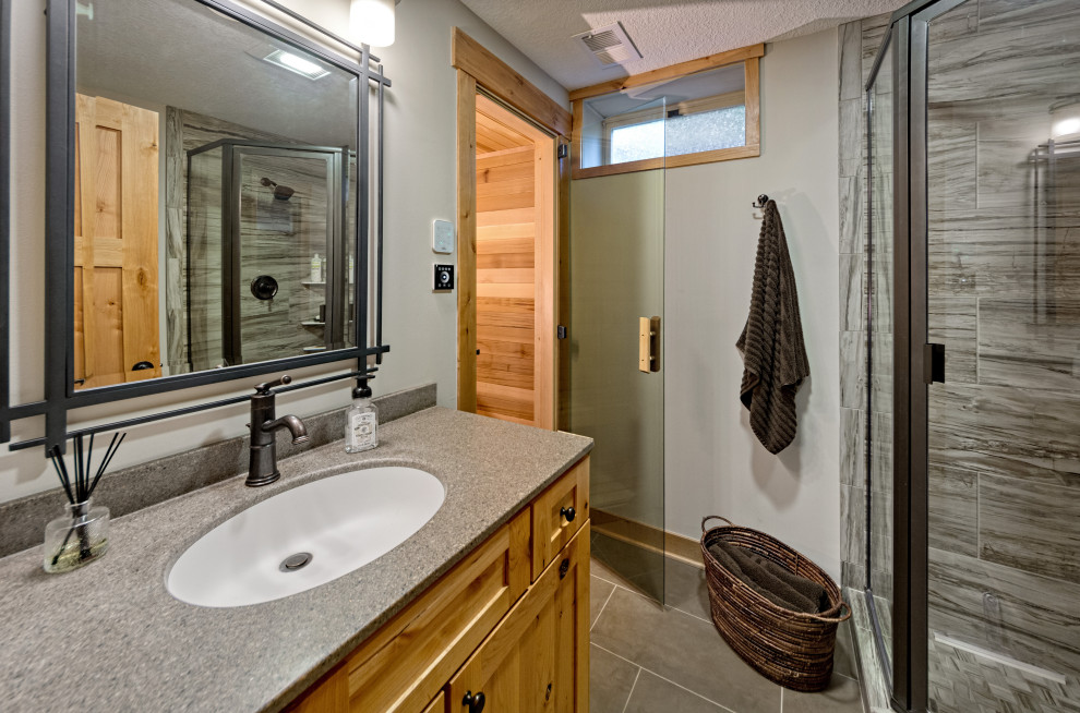 Small traditional sauna bathroom in Minneapolis with shaker cabinets, light wood cabinets, a corner shower, a two-piece toilet, multi-coloured tiles, porcelain tiles, grey walls, porcelain flooring, an integrated sink, solid surface worktops, beige floors, a hinged door, grey worktops, a single sink and a built in vanity unit.