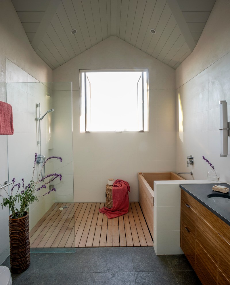 Réalisation d'une grande salle de bain principale craftsman en bois brun avec un lavabo encastré, un placard à porte plane, un plan de toilette en stéatite, un bain japonais, une douche à l'italienne, un carrelage beige, un mur beige et parquet clair.