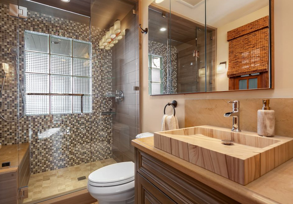 Photo of a small traditional shower room bathroom in San Diego with raised-panel cabinets, medium wood cabinets, a one-piece toilet, multi-coloured tiles, mosaic tiles, beige walls, travertine flooring, a submerged sink, limestone worktops, brown floors, a hinged door and beige worktops.