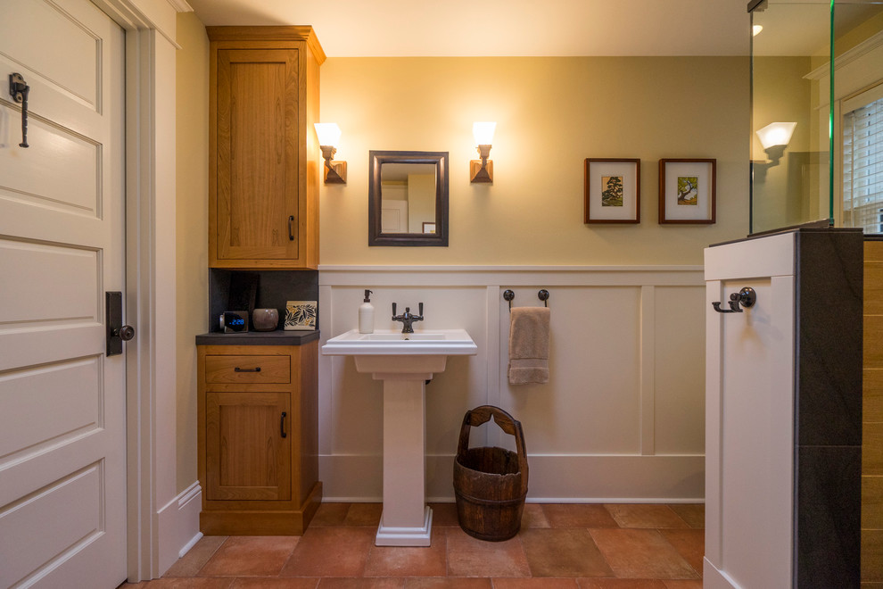 Bild på ett mellanstort amerikanskt badrum med dusch, med skåp i shakerstil, skåp i mellenmörkt trä, en toalettstol med separat cisternkåpa, svart kakel, porslinskakel, gula väggar, klinkergolv i porslin, ett piedestal handfat, kaklad bänkskiva och en hörndusch