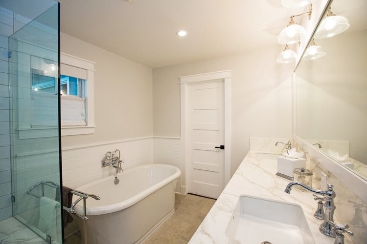 Пример оригинального дизайна: большая главная ванная комната в стиле неоклассика (современная классика) с отдельно стоящей ванной, душем в нише, раздельным унитазом, белой плиткой, плиткой кабанчик, бежевыми стенами, полом из керамической плитки, врезной раковиной, столешницей из кварцита, бежевым полом и душем с распашными дверями