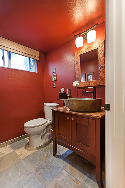 Foto på ett litet amerikanskt badrum med dusch, med ett fristående handfat, skåp i shakerstil, skåp i mellenmörkt trä, marmorbänkskiva, en toalettstol med separat cisternkåpa, flerfärgad kakel, stenkakel, röda väggar och skiffergolv
