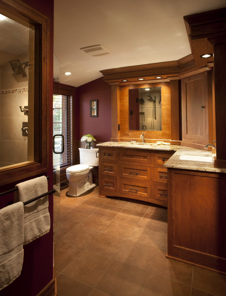 Inspiration for a large craftsman master brown floor bathroom remodel in Milwaukee with shaker cabinets, medium tone wood cabinets, red walls, an undermount sink, granite countertops and a hinged shower door