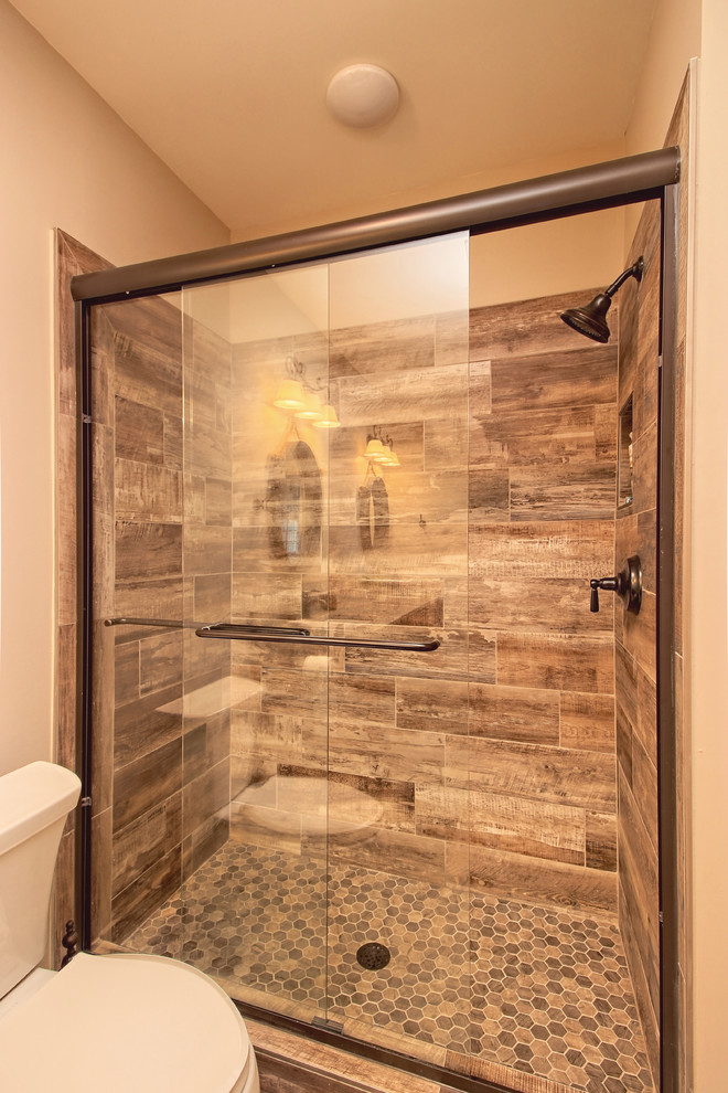 Photo of a large classic bathroom in Atlanta with raised-panel cabinets, medium wood cabinets, an alcove bath, an alcove shower, a two-piece toilet, multi-coloured tiles, ceramic tiles, beige walls, ceramic flooring, a submerged sink, granite worktops, brown floors, a sliding door and multi-coloured worktops.