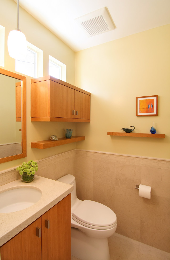Inspiration pour une petite salle de bain craftsman en bois brun avec un placard à porte plane, WC à poser, un carrelage beige, un carrelage de pierre, un mur jaune, un lavabo encastré, un sol en calcaire et un plan de toilette en calcaire.
