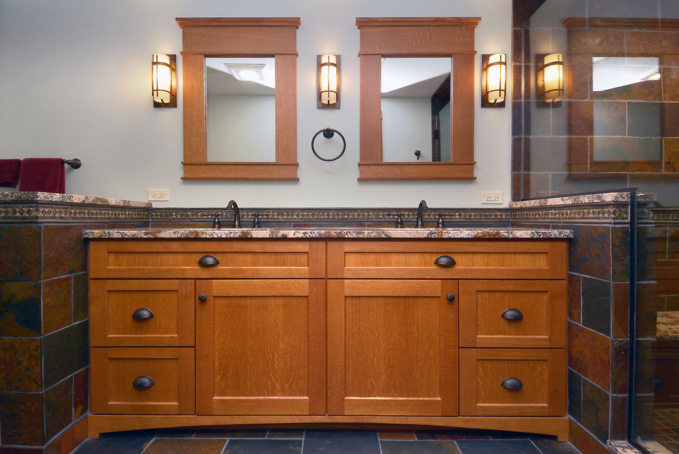 Example of a large arts and crafts master multicolored tile and stone tile slate floor corner shower design in Chicago with recessed-panel cabinets, medium tone wood cabinets, a two-piece toilet, an undermount sink and granite countertops