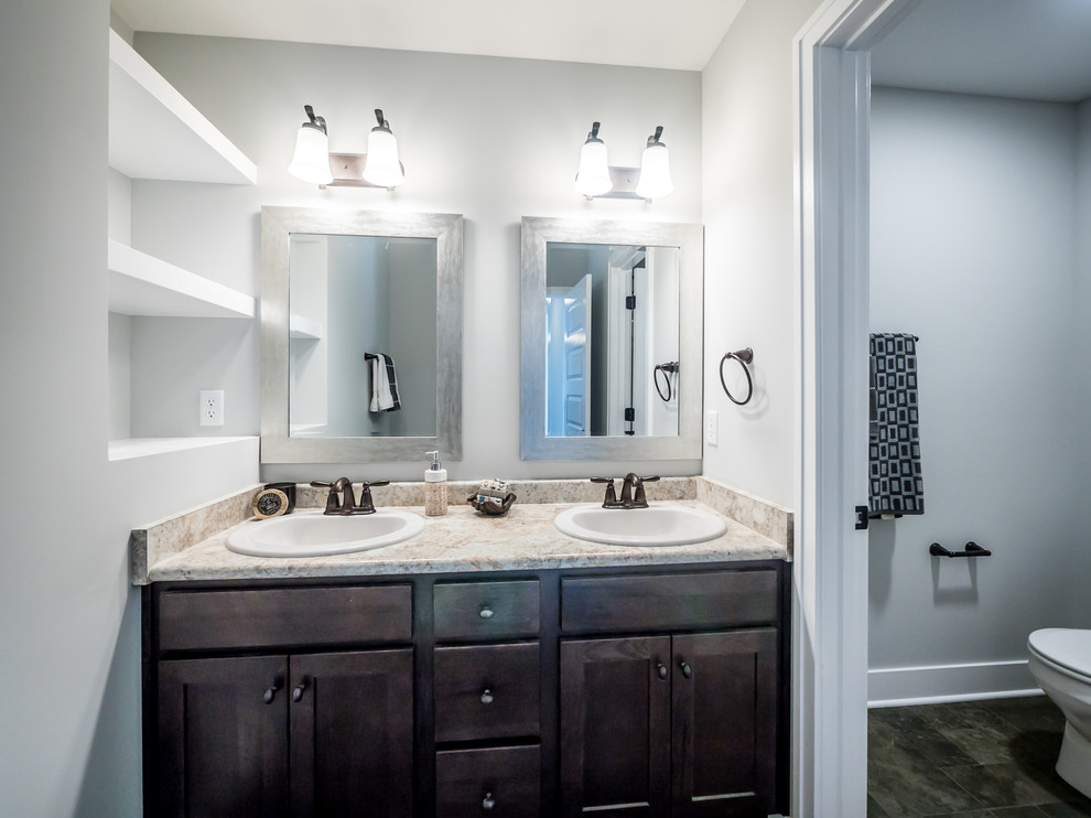 Example of a mid-sized arts and crafts 3/4 beige tile, gray tile and stone tile bathroom design in Other with flat-panel cabinets, brown cabinets, gray walls, a drop-in sink and solid surface countertops