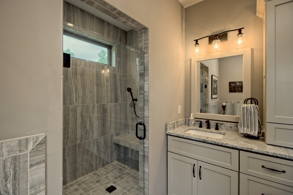 Exempel på ett stort amerikanskt flerfärgad flerfärgat en-suite badrum, med luckor med infälld panel, beige skåp, ett hörnbadkar, en dusch i en alkov, en toalettstol med separat cisternkåpa, grå kakel, keramikplattor, beige väggar, klinkergolv i keramik, ett undermonterad handfat, granitbänkskiva, grått golv och dusch med gångjärnsdörr