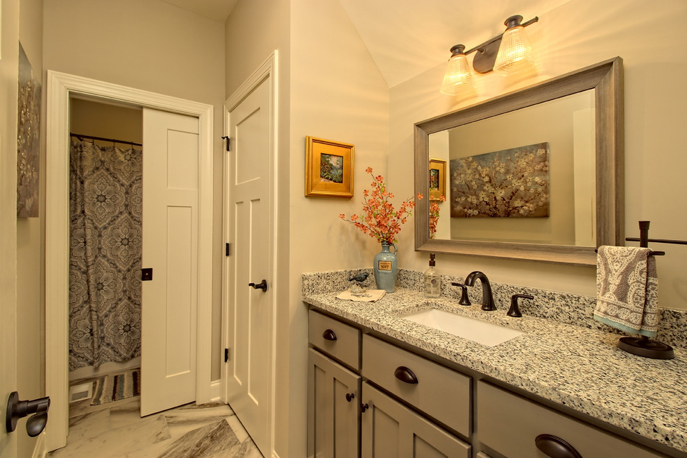 На фото: большая ванная комната в стиле кантри с фасадами в стиле шейкер, серыми фасадами, ванной в нише, душем над ванной, раздельным унитазом, серой плиткой, керамической плиткой, бежевыми стенами, полом из керамической плитки, врезной раковиной, столешницей из гранита, серым полом, шторкой для ванной и разноцветной столешницей