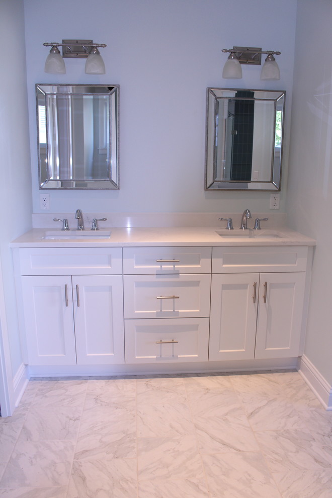 Photo of a large traditional ensuite bathroom in St Louis with shaker cabinets, white cabinets, a freestanding bath, a corner shower, grey walls, marble flooring, a submerged sink, marble worktops, white floors and a hinged door.