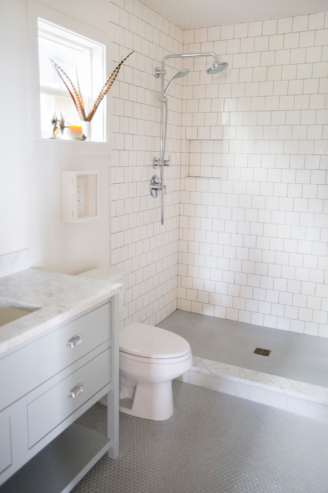 Bild på ett litet vintage badrum med dusch, med luckor med infälld panel, grå skåp, en öppen dusch, en toalettstol med separat cisternkåpa, vit kakel, tunnelbanekakel, vita väggar, mosaikgolv, ett undermonterad handfat och marmorbänkskiva