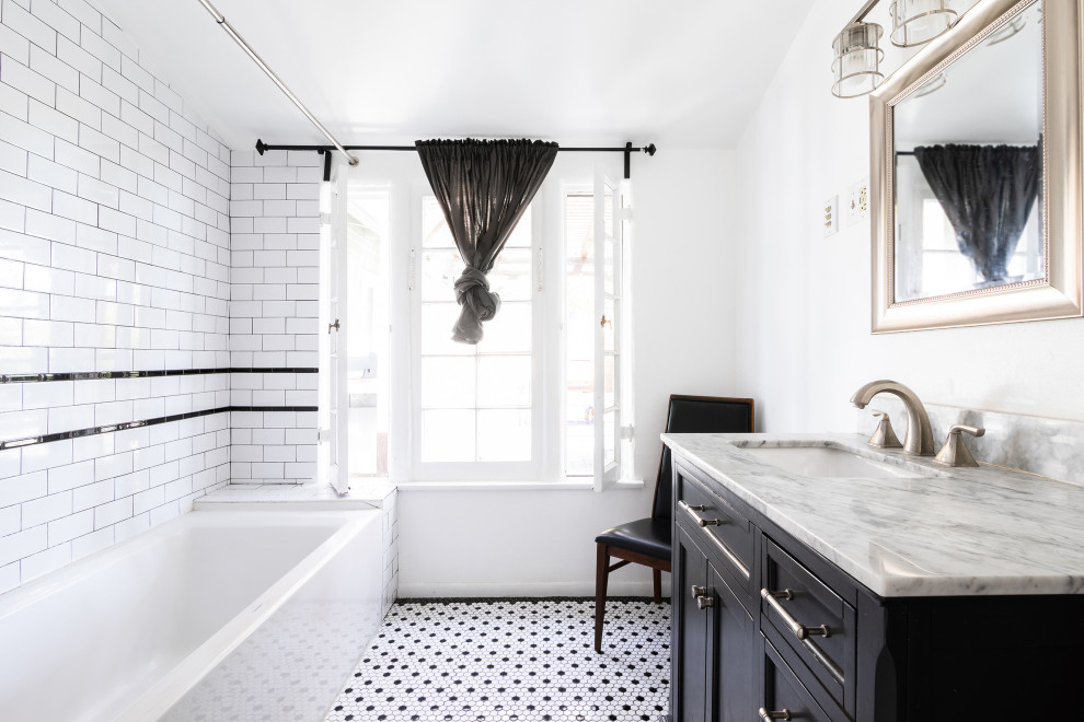 Amerikansk inredning av ett mellanstort grå grått en-suite badrum, med skåp i shakerstil, svarta skåp, ett badkar i en alkov, en dusch/badkar-kombination, svart och vit kakel, tunnelbanekakel, vita väggar, mosaikgolv, ett undermonterad handfat, marmorbänkskiva och svart golv