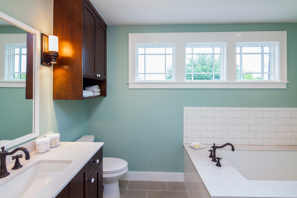 Exemple d'une salle de bain principale chic en bois brun de taille moyenne avec un lavabo encastré, un placard avec porte à panneau encastré, un plan de toilette en quartz modifié, une baignoire encastrée, WC à poser, un carrelage blanc et un mur bleu.