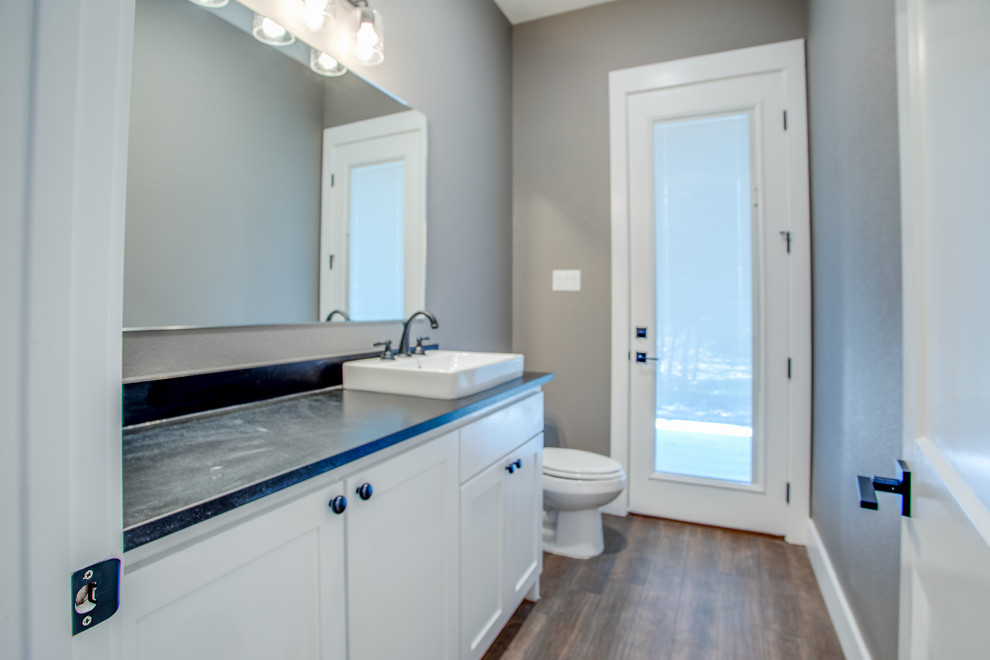 Idéer för ett mellanstort amerikanskt svart badrum med dusch, med luckor med infälld panel, vita skåp, en toalettstol med separat cisternkåpa, grå väggar, klinkergolv i keramik, ett fristående handfat, granitbänkskiva och brunt golv