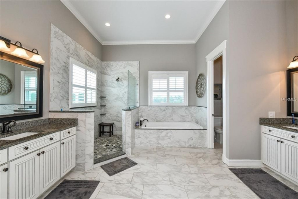 Exempel på ett stort amerikanskt flerfärgad flerfärgat en-suite badrum, med luckor med infälld panel, vita skåp, ett platsbyggt badkar, en öppen dusch, en toalettstol med hel cisternkåpa, grå kakel, porslinskakel, grå väggar, klinkergolv i porslin, ett undermonterad handfat, granitbänkskiva, vitt golv och med dusch som är öppen