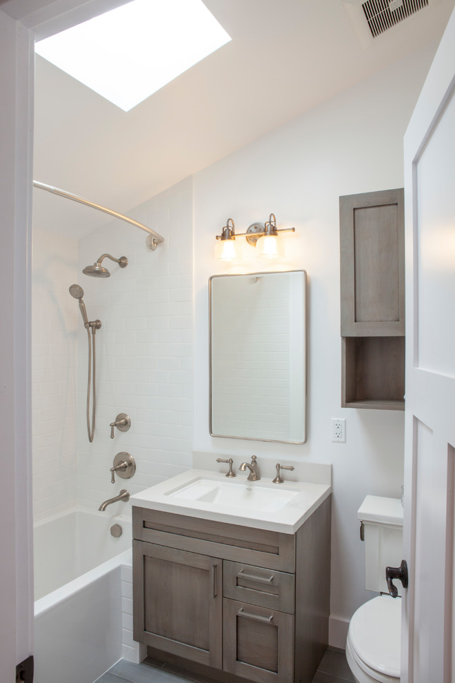 Modelo de cuarto de baño infantil, clásico renovado, pequeño, con armarios estilo shaker, puertas de armario grises, bañera encastrada, combinación de ducha y bañera, sanitario de dos piezas, baldosas y/o azulejos blancos, baldosas y/o azulejos de cemento, paredes blancas, suelo de baldosas de porcelana, lavabo bajoencimera, encimera de cuarzo compacto y suelo gris