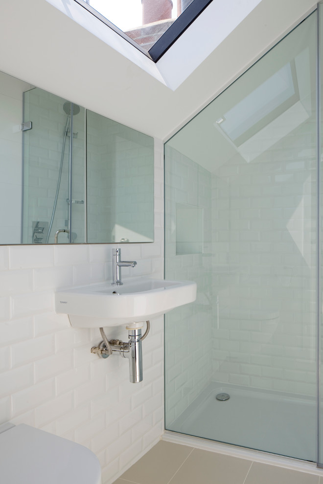 This is an example of a small contemporary ensuite bathroom in London with a wall-mounted sink, a freestanding bath, a built-in shower, a wall mounted toilet, white tiles, metro tiles, white walls and porcelain flooring.