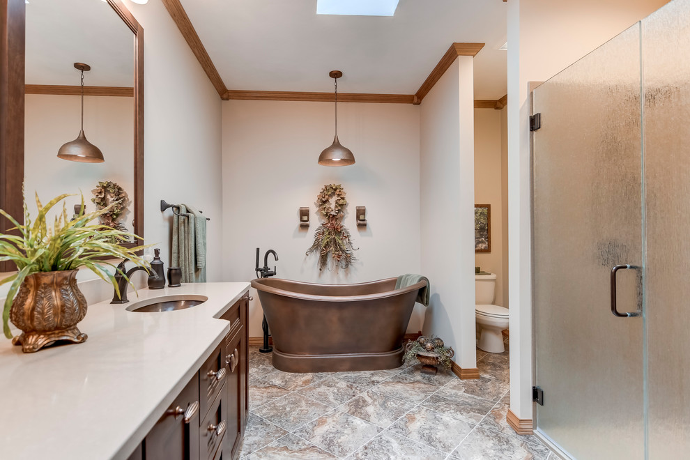 Cette image montre une salle de bain traditionnelle en bois brun avec une baignoire indépendante, une douche à l'italienne, un sol en vinyl, un lavabo encastré, un plan de toilette en quartz modifié, une cabine de douche à porte battante et un plan de toilette beige.