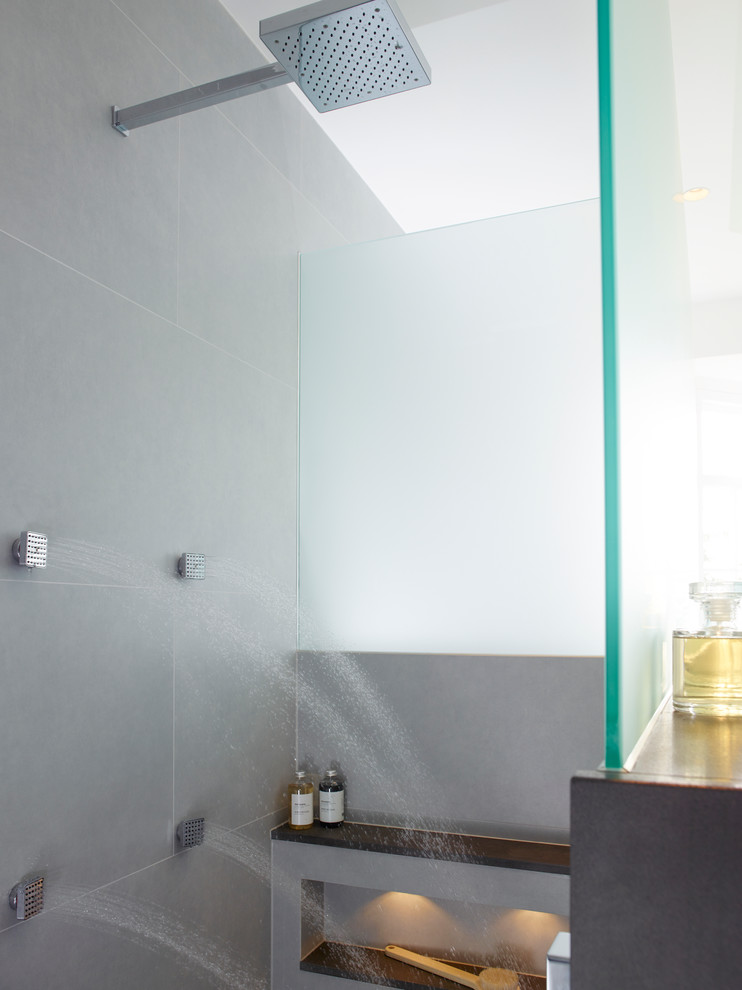 Cette image montre une salle de bain principale design avec un lavabo suspendu, une baignoire indépendante, un carrelage gris, des carreaux de céramique, un mur gris et un sol en carrelage de porcelaine.
