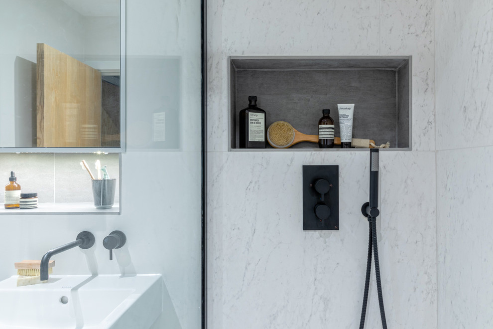 Photo of a small scandinavian ensuite bathroom in London with a built-in bath, a walk-in shower, a wall mounted toilet, white tiles, porcelain tiles, white walls, porcelain flooring, a wall-mounted sink and grey floors.