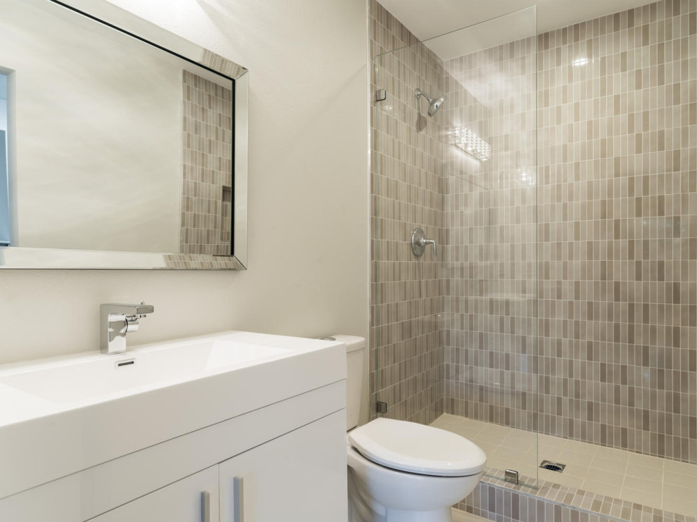 Bild på ett mellanstort funkis vit vitt en-suite badrum, med släta luckor, vita skåp, en dusch i en alkov, en toalettstol med separat cisternkåpa, grå kakel, porslinskakel, grå väggar, klinkergolv i porslin, grått golv och dusch med gångjärnsdörr