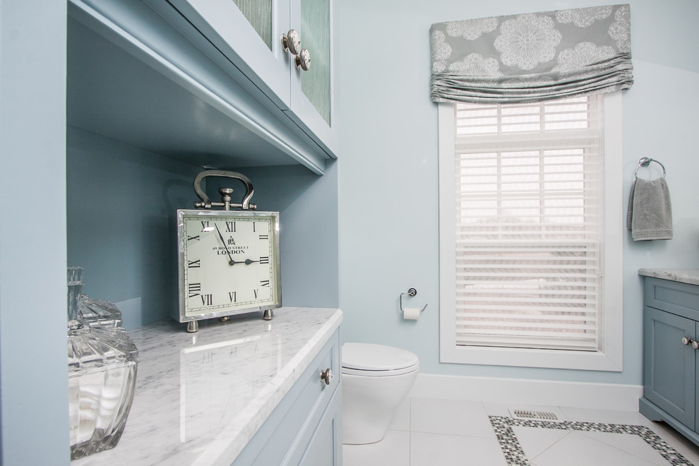Aménagement d'une salle de bain principale classique de taille moyenne avec un placard en trompe-l'oeil, des portes de placard bleues, un plan de toilette en marbre, un carrelage blanc et un mur bleu.