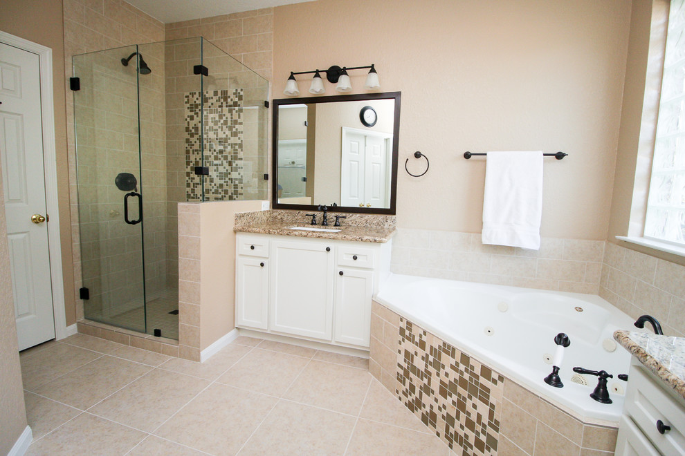 Cette photo montre une grande salle de bain principale chic avec un placard à porte shaker, des portes de placard blanches, une baignoire d'angle, une douche d'angle, un carrelage beige, des carreaux de céramique, un mur beige, un sol en carrelage de céramique, un lavabo encastré et un plan de toilette en granite.