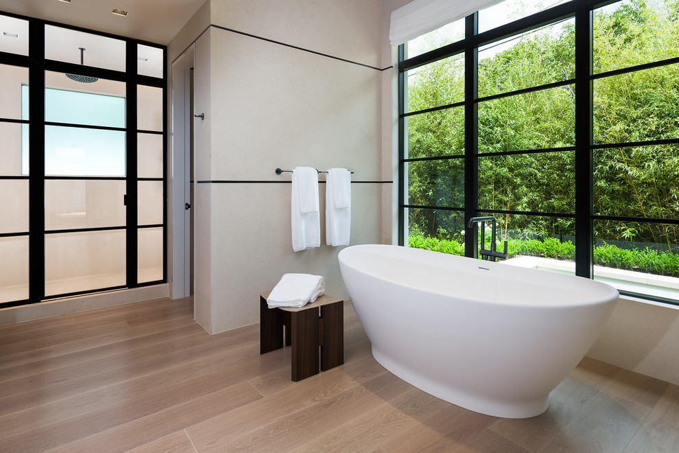 Пример оригинального дизайна: большая главная ванная комната в современном стиле с отдельно стоящей ванной, бежевыми стенами, светлым паркетным полом, бежевым полом, душем в нише и белой плиткой