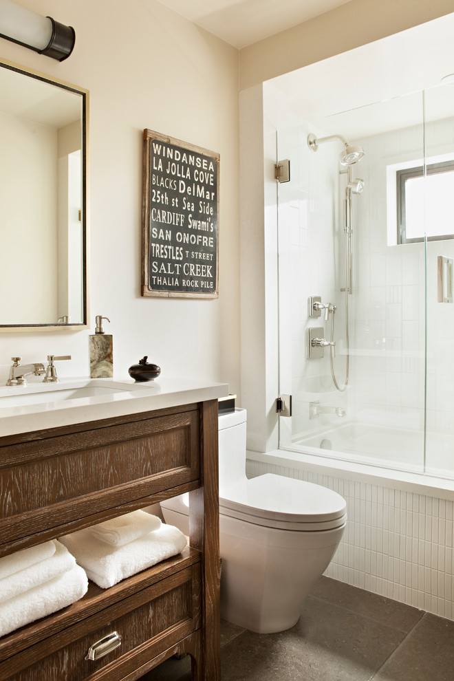 Foto på ett funkis badrum, med ett undermonterad handfat, luckor med infälld panel, skåp i mellenmörkt trä, bänkskiva i kvarts, ett undermonterat badkar, en dusch/badkar-kombination, en toalettstol med hel cisternkåpa, vit kakel, keramikplattor och beige väggar